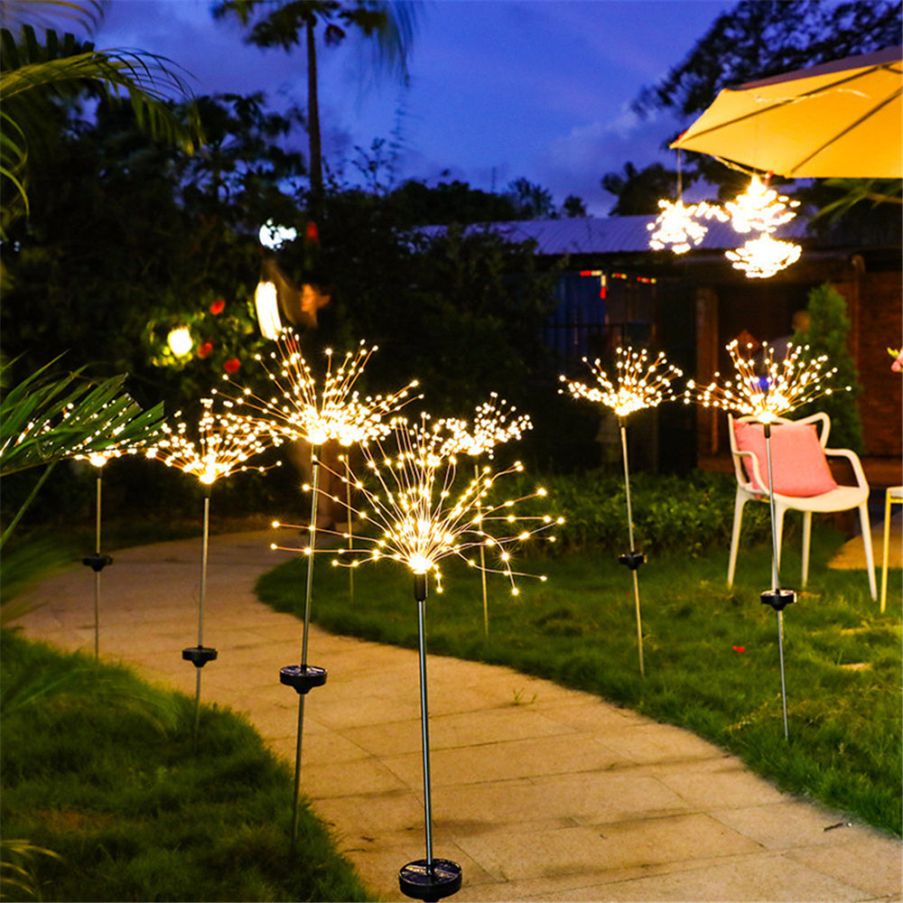 A row of solar fireworks illuminating a garden path at dusk.