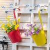 Tre realistiske gulblå guldsmedeklemmer hænger på en hvid træplade med potteblomster.
