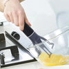A hand is using a black automatic pan stirrer to mix ingredients in a clear glass bowl.
