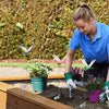 En kvinde planter realistiske guldsmedeklips i jorden i et havebed.