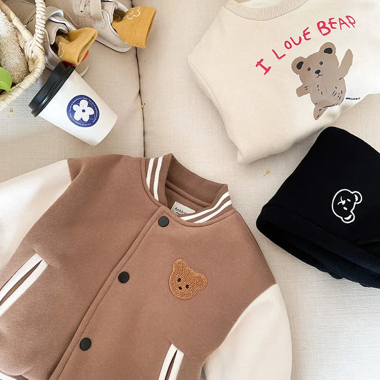 A brown fleece-lined corduroy jacket with white stripes and a small bear patch on the chest, displayed on a light surface.