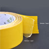 Roll of yellow heavy-duty double-sided fiberglass tape showing the release paper and adhesive layer.