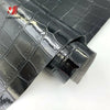 Close-up of black crocodile pattern faux leather fabric rolled up for crafting