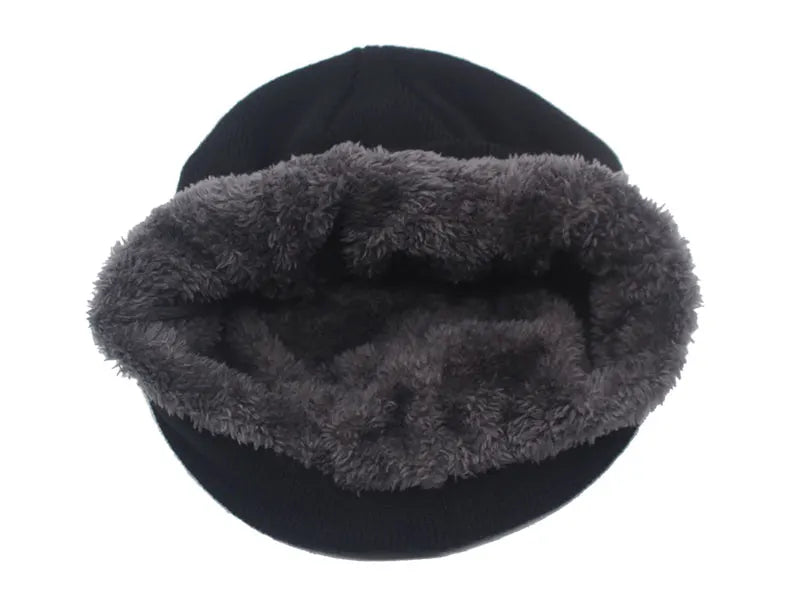 A black knitted winter beanie hat with a thick, gray faux fur trim.
