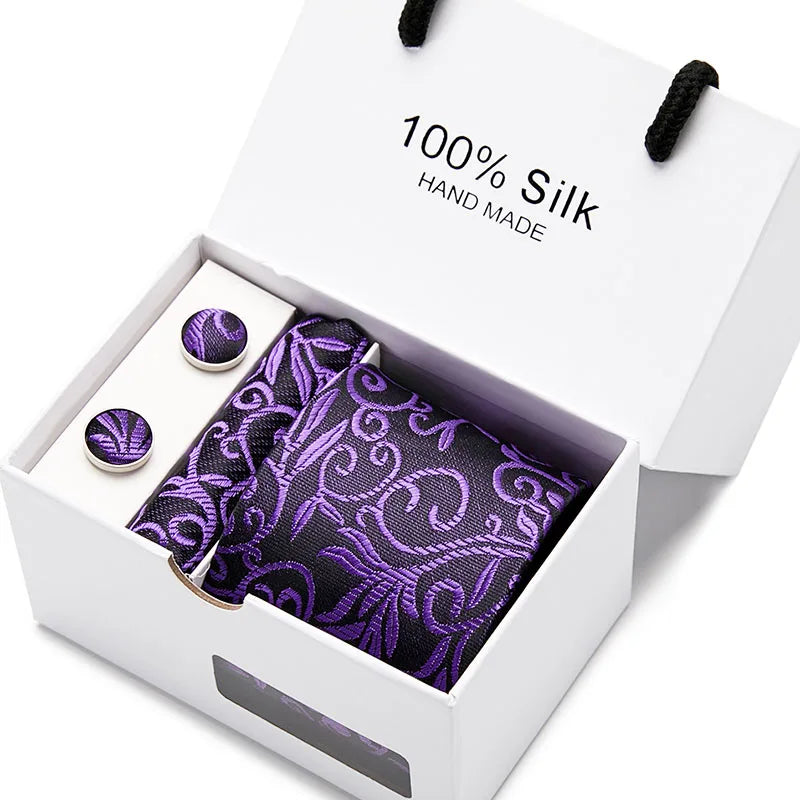 Una caja blanca con una corbata de seda morada estampada en cachemir y dos botones de seda.