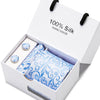 Caja blanca con corbata de seda azul marino estampada de cachemira hecha a mano y un pequeño accesorio redondo.
