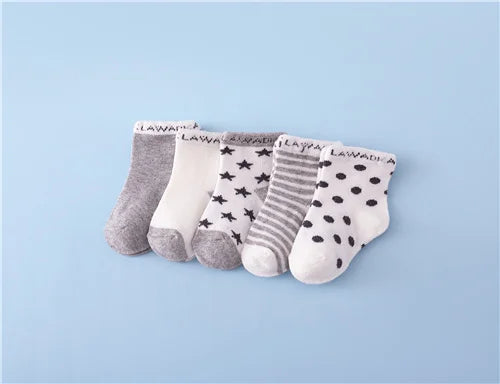 A set of nine baby socks in various gray, white, and striped patterns laid out on a light blue background.