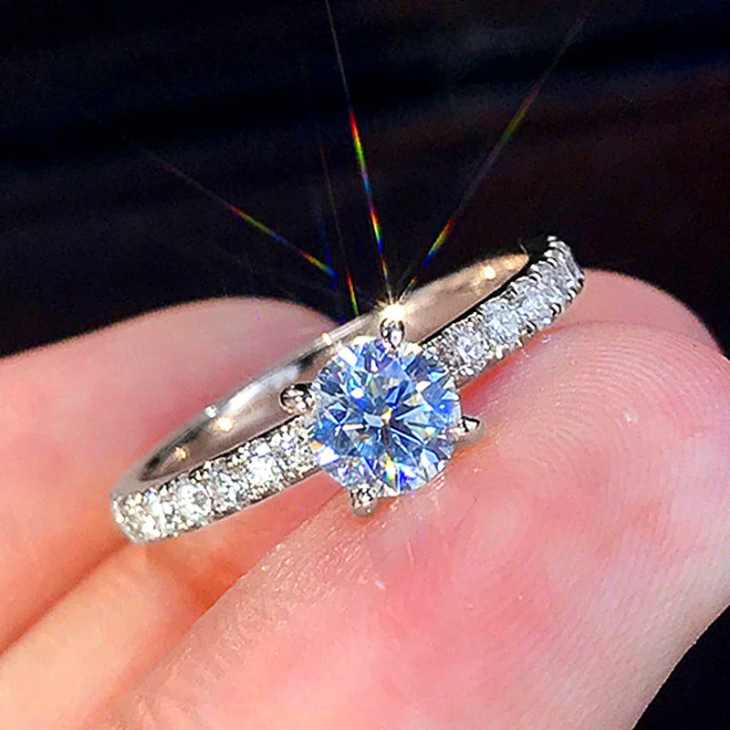 Nærbilde av en klassisk rund cubic zirconia-brurefonje som glitrer på en finger.