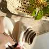 A close-up of a beige fleece-lined corduroy jacket sleeve with brown stripes resting on a woven mat.