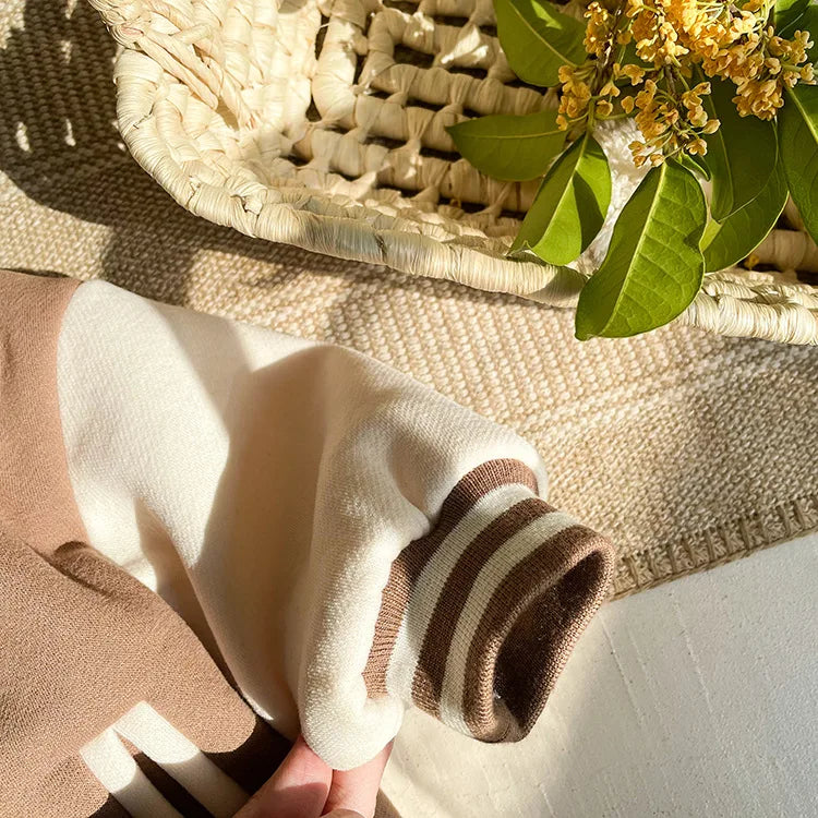 A close-up of a beige fleece-lined corduroy jacket sleeve with brown stripes resting on a woven mat.