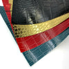 A stack of faux leather fabric strips in various colors including black, gold, red, and blue crocodile patterns.