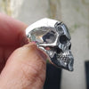 Ein silberner Gothic-Totenkopf-Bikerring am Finger.