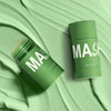 A green tube of mask product is shown on a light green, glossy surface.