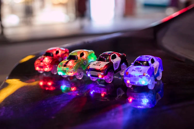 A set of glowing magnetic race cars with ramps and bridges displayed on a dark surface.