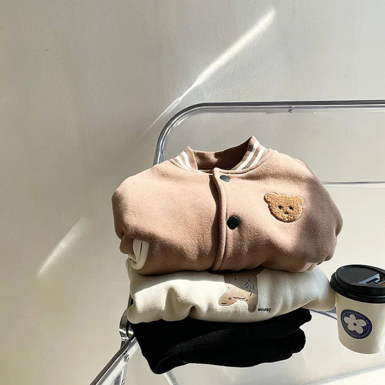 A tan fleece-lined corduroy jacket for a toddler is displayed on a clear stand.