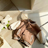 A brown corduroy jacket with white stripes and a brown patch is displayed on a woven mat next to a white stuffed animal.