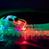 A small, glowing electric car is racing along a translucent magnetic track with ramps and bridges.
