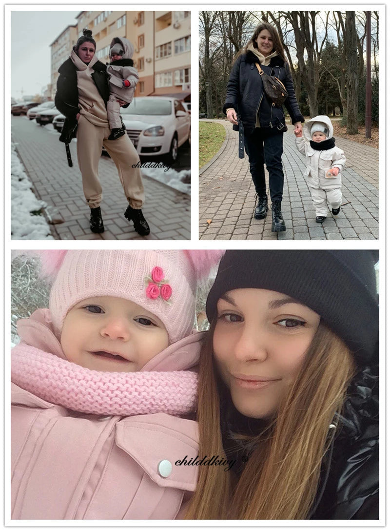A young woman holds a baby wearing a pink winter down jacket and pants set with a faux fur hood.