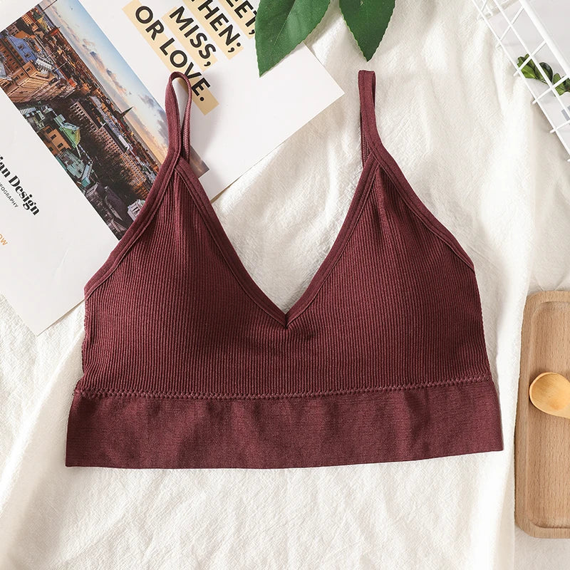 A maroon seamless U-back bralette with adjustable straps and removable pads displayed on a white fabric.