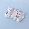 A set of five white and blue patterned cotton baby socks laid out on a light blue background.