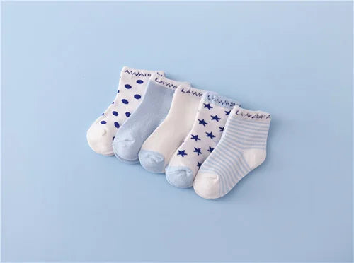 A set of five white and blue patterned cotton baby socks laid out on a light blue background.