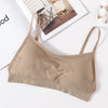 A beige seamless U-back bralette with adjustable straps lying on a white surface.