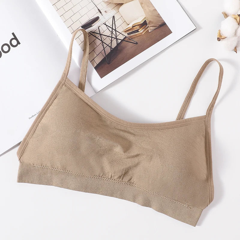 A beige seamless U-back bralette with adjustable straps lying on a white surface.