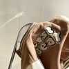 A close-up of a tan corduroy jacket with a beige bear graphic on the sleeve, shown on a hanger.