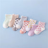 A set of ten striped cotton baby socks in various pastel colors and patterns laid out on a light blue background.