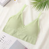 A light green seamless U-back bralette top displayed on a white background next to a green palm leaf.