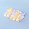 A set of five yellow and white striped cotton baby socks laid out on a light blue background.