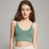 A young woman models a sage green seamless U-back bralette top and light pants.
