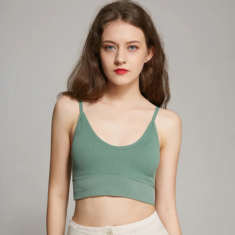A young woman models a sage green seamless U-back bralette top and light pants.