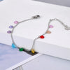 Collar de cadena plateada con colgantes de gemas CZ coloridas sobre una superficie blanca.