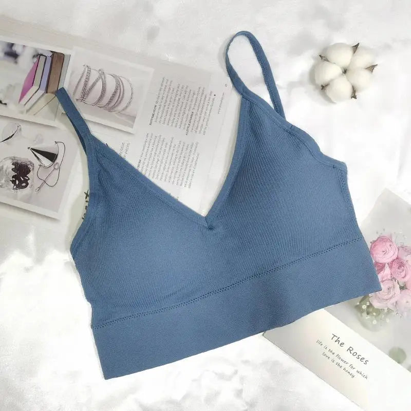A dusty blue seamless U-back bralette with a V-neck and removable pads is displayed on a white surface.