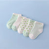A set of five pastel green and white striped cotton baby socks laid out on a light blue background.