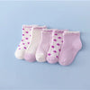 A set of five baby socks in various shades of pink and white with small purple stars.