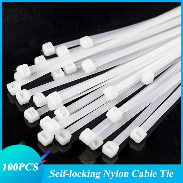 A collection of white self-locking nylon cable ties or zip ties laid out on a dark surface.