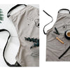 A light gray cotton apron featuring a cartoon bear design and dark green foliage details.