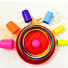 A collection of colorful plastic stacking cups and rings arranged on a white surface.
