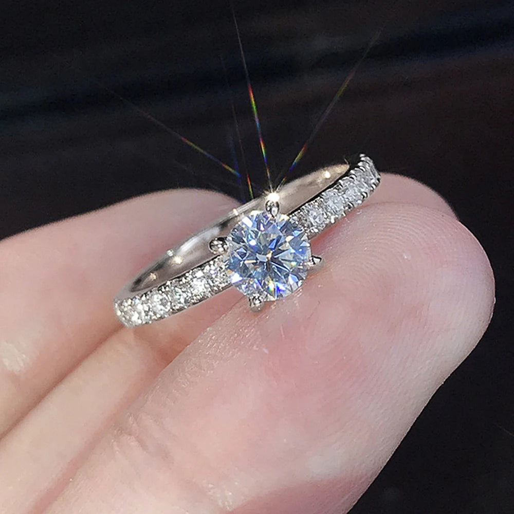 Nærbilde av en klassisk rund kubisk zirkonia-bryllupsring på en finger.
