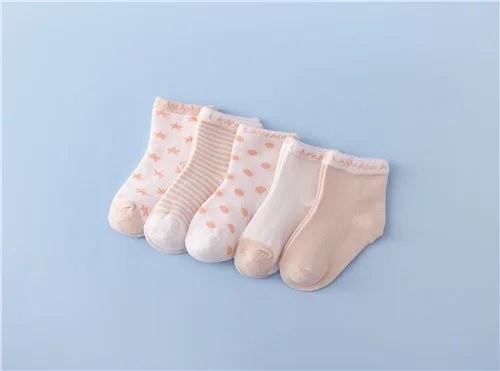 A set of five light pink and white patterned cotton baby socks laid out on a light blue background.