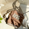 A brown fleece-lined corduroy jacket with a beige bear graphic lying on a woven mat.