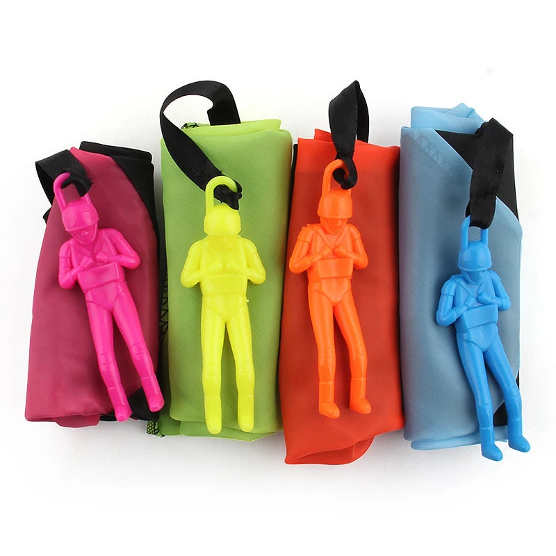 Cinco juguetes paracaídas hechos a mano para niños en colores rosa, verde lima, naranja y azul.