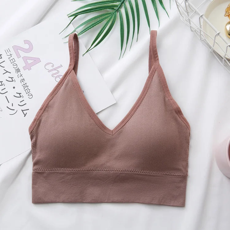 A mauve seamless U-back bralette with removable pads is displayed on a white background next to green leaves.
