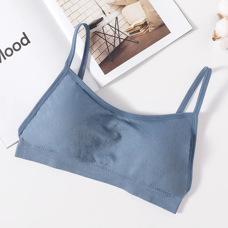A light blue seamless U-back bralette with adjustable straps lying on a white surface.