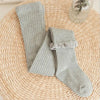 Gray ribbed cotton tights with a lace cuff lying on a woven mat.