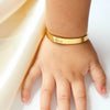 Nahaufnahme eines Kinderhandgelenks mit einem goldenen Namensarmband, graviert mit dem Namen Victoria.