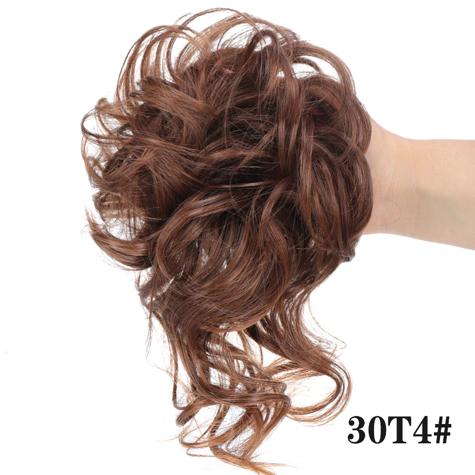 Primer plano de cabello rizado castaño rojizo recogido en un moño desordenado con una banda elástica.