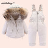 A white baby winter down jacket and pants set with a faux fur hood displayed on a light background.